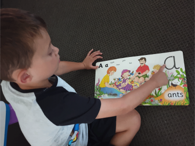 boy tracing letters in a book