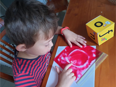 Boy tracing a letter in a bag with colored gel