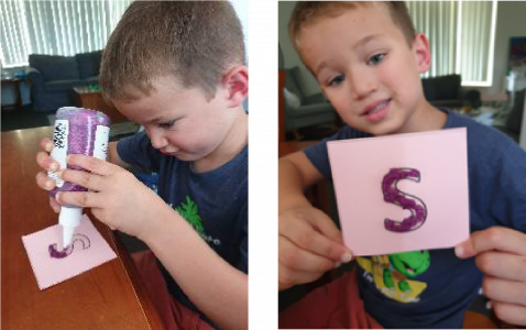 boy holding card with glue letter