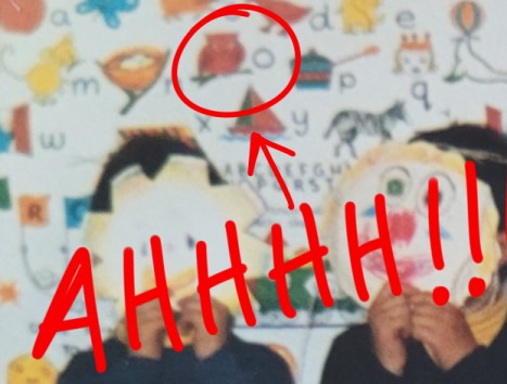 A zoomed-in image of the same students from the previous image with white paper masks over their faces, with the focus being on the alphabet board. The letter 'O' and the image of an owl are circled in red with a red arrow and the word 'AHHH' over the image.