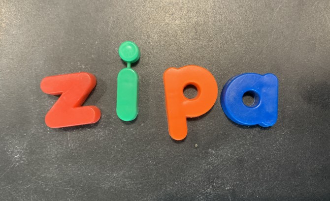 An image of colourful magnet letters: z, i, p, a on a grey background